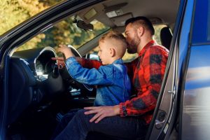 A handsome father pointing at something while teaching his teenage son how to drive, offering guidance and advice during a driving lesson. 