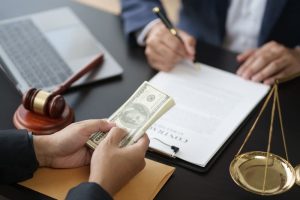 Close-up of a young lawyer signing a contract after finalizing a deal with a client, as the client hands over contingency fees to the attorney.