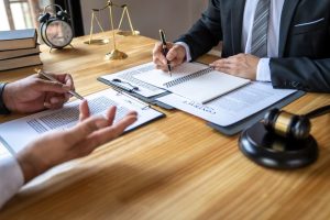 A business lawyer discussing contract paperwork with a client in the courtroom, offering legal advice on legislation to assist their customer.