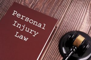 "Personal Injury Law" written on a book with a judge's gavel resting on a wooden table background.