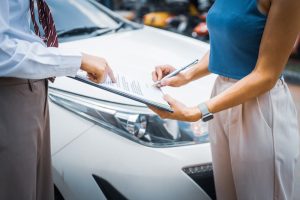 A young businesswoman sits at her desk, evaluating car insurance options by comparing premiums, deductibles, and coverage to understand the policies thoroughly.