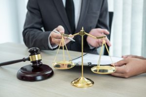 Male attorney or legal advisor discussing a case with a client during a meeting, reviewing contract documents in an office. Law, justice, and litigation concept.