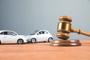 A court gavel rests on a table surrounded by toy cars, symbolizing the legal proceedings related to an accident.