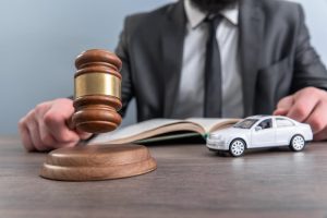 Judge seated at a desk with a gavel in hand, a small toy car placed on the table, symbolizing a legal case involving an automobile accident or insurance claim.