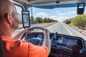 A truck driver focused on the road, driving straight along a highway.