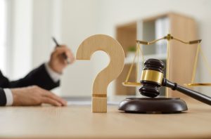 Close-up of a wooden question mark and gavel on a judge's table in a courtroom or on a lawyer's desk.