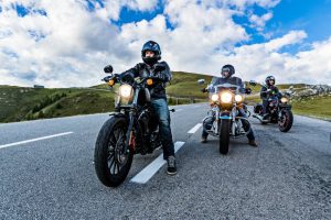 Motorcyclists riding on a highway, surrounded by scenic landscapes, wearing helmets and protective gear for safety.