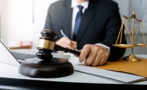 A business meeting with lawyers discussing contract documents, accompanied by a brass scale on the desk in an office setting. 