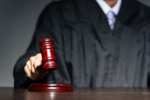 A judge striking a gavel in court during a trial. 