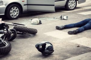 A motorcyclist's helmet and motorbike lying on the street after a collision with a car. 