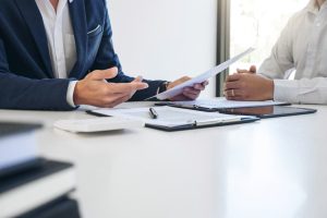 An insurance agent presents and consults with a customer about policy details, awaiting their response to finalize the discussion.