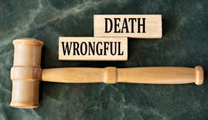 Wooden blocks spelling "WRONGFUL DEATH" on a green background, accompanied by a judge's gavel.