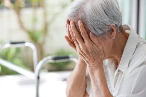 Depressed Asian senior woman struggling with anxiety and emotional distress, sitting alone at home. The elderly patient appears tired and overwhelmed, reflecting symptoms of depression and mood disorders. 