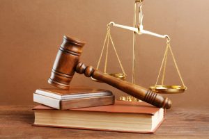 A judge's gavel and scales set against a brown background.